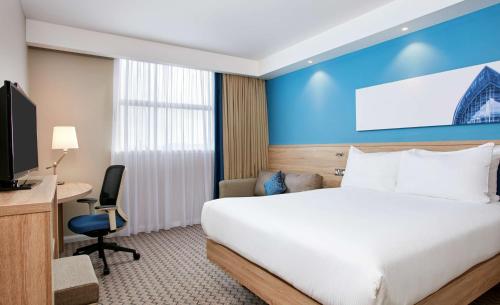 a hotel room with a bed and a desk and a tv at Hampton by Hilton Glasgow Central in Glasgow