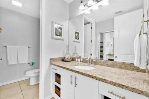 a white bathroom with a sink and a toilet at Waterfront condo with private boat slip - best of beach and bay! in South Padre Island