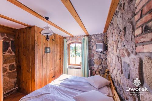 a bedroom with a bed and a stone wall at Agroturystyka "Dworek u Pelców" in Ryn