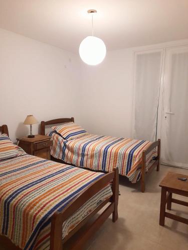 a bedroom with two beds and a lamp and a table at Rabastens in Mar de las Pampas