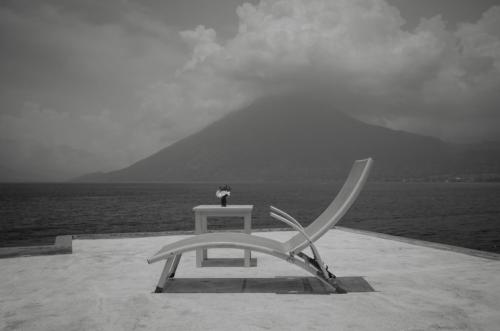 a white chair sitting on a table next to the ocean at Anzan Atitlan in San Marcos La Laguna