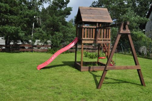 a playground with a red slide in a yard at OSADA GRZYBOWSKI MŁYN apartamenty z dużym ogrodem KAISERÓWKA in Grzybowo