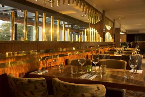 a restaurant with a wooden table and chairs and wine glasses at DoubleTree by Hilton Edinburgh - Queensferry Crossing in North Queensferry