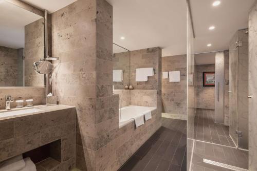 La salle de bains est pourvue d'une baignoire, d'un lavabo et d'une douche. dans l'établissement Hilton The Hague, à La Haye