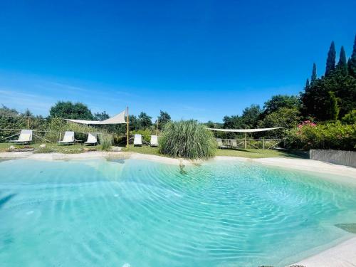 a large swimming pool with chairs in a yard at Villa Armena Relais in Buonconvento