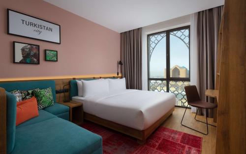 Habitación de hotel con cama y sofá en Hampton By Hilton Turkistan en Türkistan