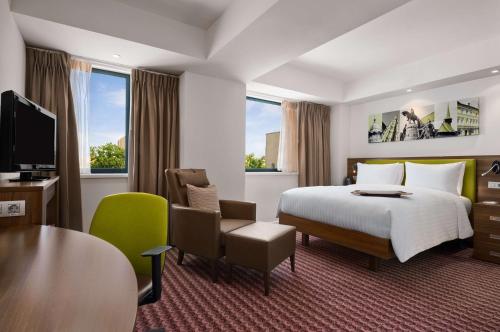 a hotel room with a bed and a desk and chair at Hampton by Hilton Cluj-Napoca in Cluj-Napoca