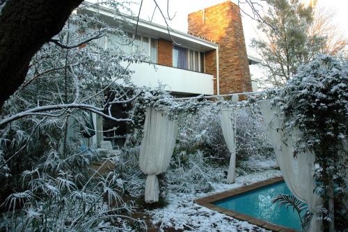 een tuin bedekt met sneeuw met gordijnen en een zwembad bij Amethyst Suites (Part of Emerald Guest House) in Springs