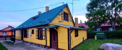 a small yellow house with a blue roof at Dom Zajezdny in Białowieża