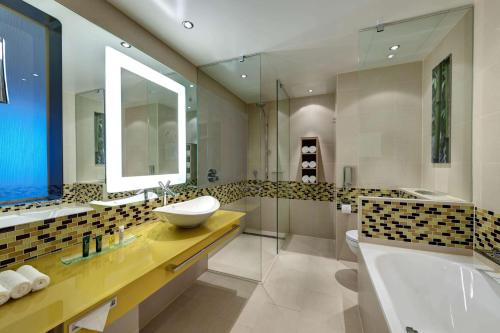 a bathroom with a sink and a tub and a mirror at Hilton Frankfurt Airport in Frankfurt