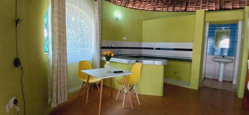 a kitchen with yellow chairs and a table with a sink at Omnia Resort in Mtwapa
