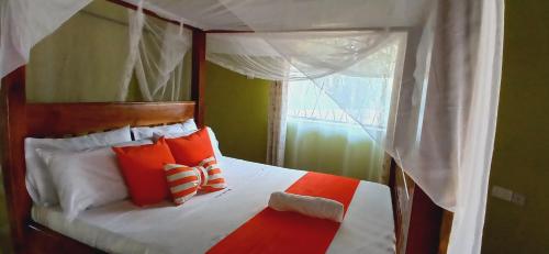 a bedroom with a canopy bed with orange and white pillows at Omnia Resort in Mtwapa