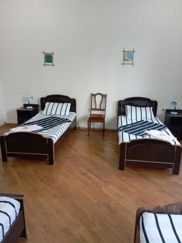 a room with three beds and a chair in it at Art House Hostel Aleksandr in Kutaisi
