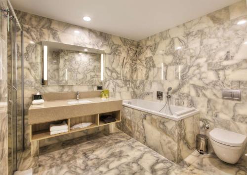 ein Badezimmer mit einem Waschbecken, einer Badewanne und einem WC in der Unterkunft Hilton Garden Inn Isparta in Isparta