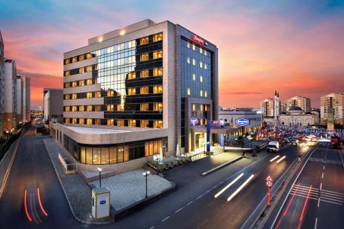ein Gebäude in einer Stadtstraße mit einer belebten Straße in der Unterkunft Hampton by Hilton Istanbul Kayasehir in Istanbul