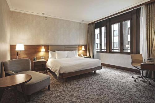 una camera d'albergo con letto, scrivania e sedia di Hilton Milan a Milano