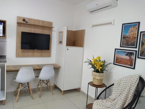 a living room with a table and chairs and a television at Pousada Loft São Chico - Exclusiva para casais in São Francisco do Sul