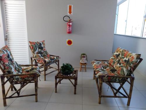 a room with three chairs and a table with a plant at Pousada Loft São Chico - Exclusiva para casais in São Francisco do Sul