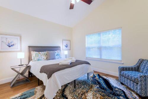 a bedroom with a bed and a chair and a window at Calypso Cottage in Bluffton