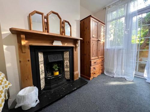 uma sala de estar com lareira e uma janela em Nice Bedroom with Private Garden Woodleigh Avenue em Birmingham