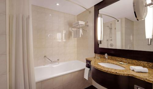 a bathroom with a bath tub and a sink and a bath tub at Hilton Munich Park in Munich