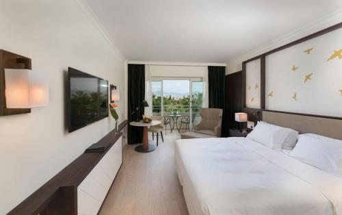 a hotel room with a large white bed and a table at Hilton Nicosia in Nicosia