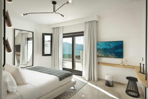 a white bedroom with a bed and a large window at Sulià House Porto Rotondo, Curio Collection by Hilton in Porto Rotondo