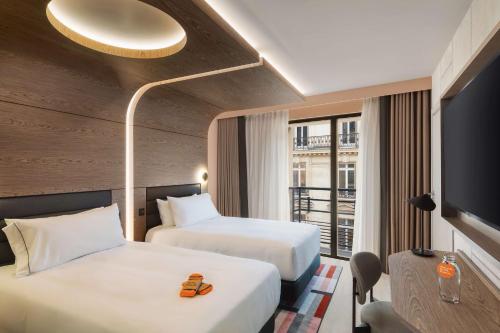 a hotel room with two beds and a tv at Canopy By Hilton Paris Trocadero in Paris