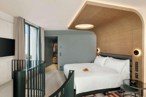 une chambre avec un grand lit blanc et un escalier dans l'établissement Canopy By Hilton Paris Eiffel Tower, à Paris