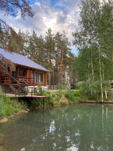 eine Blockhütte neben einem Fluss mit Bäumen in der Unterkunft Dobri Dom v Borovom in Borovoye