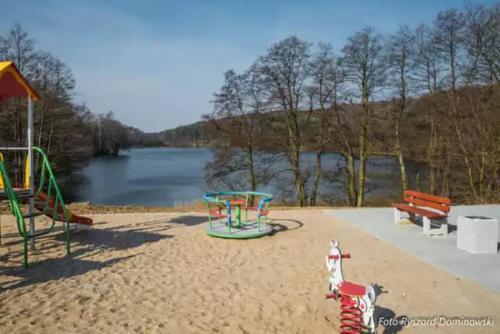 un parque con parque infantil, banco y agua en Lawendowy Wypas, en Mierzeszyn