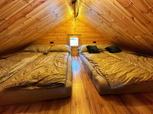 two beds in a room with wooden walls at Lawendowy Wypas in Mierzeszyn