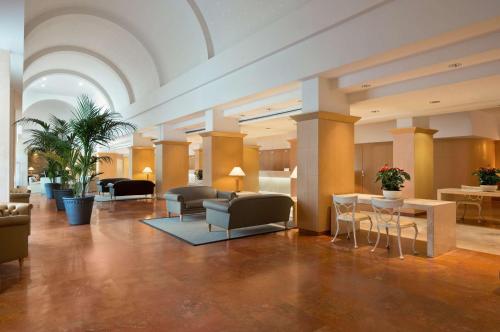 a lobby with chairs and tables in a building at Hilton Rome Airport in Fiumicino