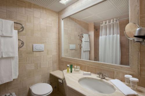 a bathroom with a sink and a toilet and a mirror at Hilton Rome Airport in Fiumicino