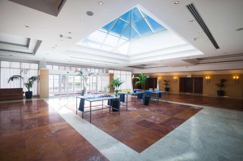 a large lobby with tables and a large skylight at Hilton Rome Airport in Fiumicino