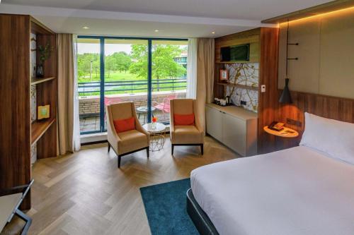 DoubleTree by Hilton Royal Parc Soestduinen في Soestduinen: غرفه فندقيه بسرير وكرسيين