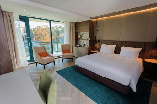 a bedroom with a large white bed and chairs at DoubleTree by Hilton Royal Parc Soestduinen in Amersfoort