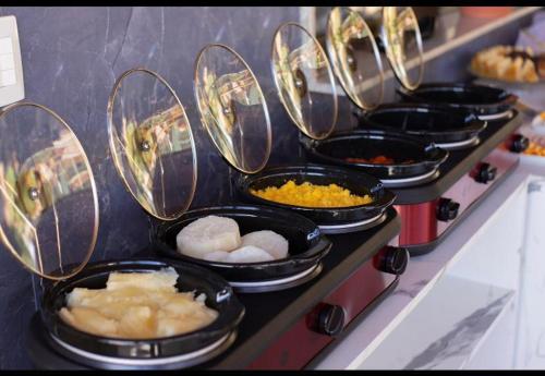 una fila di padelle riempite con diversi tipi di alimenti di POUSADA KALUKA a Bezerros