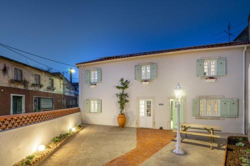 a white house with a bench in the courtyard at Gardenland House Leiria in Leiria