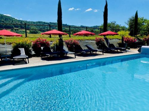 a swimming pool with chairs and red umbrellas at Les Villas du Domaine de Suzel in Vignieu