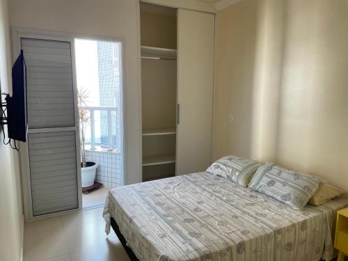 a bedroom with a bed and a large window at Apartamento Ubatuba Toninhas in Ubatuba