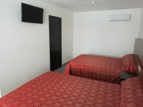 um quarto de hotel com duas camas e uma televisão em HOTEL QUINTERO em Teapa