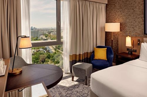 a hotel room with a bed and a desk and a window at Hilton Vienna Park in Vienna