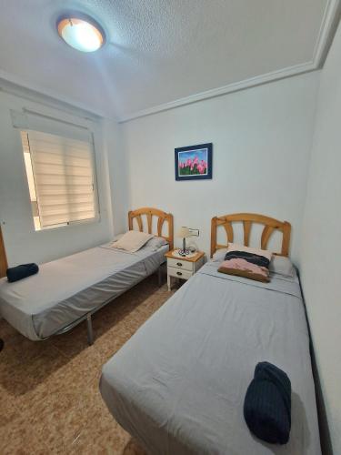 - 2 lits dans une petite chambre avec fenêtre dans l'établissement Casa Margarita, à Torrevieja