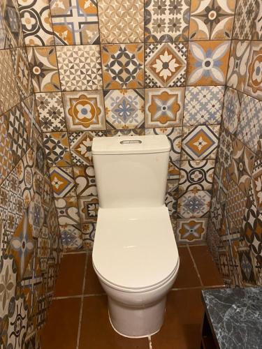 a toilet in a bathroom with tiles on the wall at RUAJ HOSTAL -Wellness-Colonial-Exclusive- in Antigua Guatemala