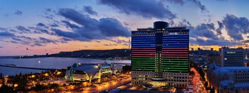 a tall building with lights on it in a city at Hilton Baku in Baku