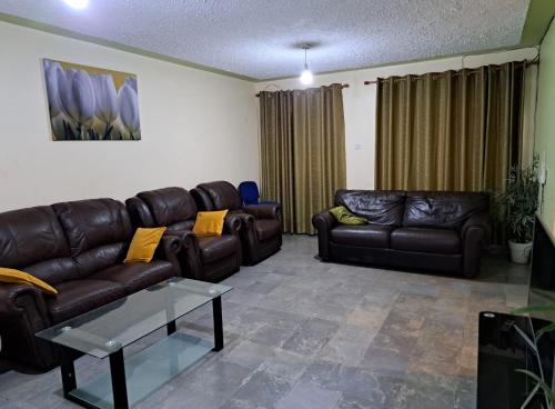 a living room with leather couches and a coffee table at Mfalme House, Ngoingwa Estate, 100 Metres from Thika-Mangu Rd, Close to Thika City Centre - Free Parking, Fast Wi-Fi, Smart TV, 2 Bedrooms Perfect for a Family of 2-4 Members in Thika