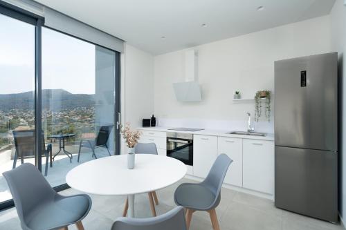 ポルト・ラフティにあるWhite Cliff Luxury Suites by A&D Propertiesの白いキッチン(白いテーブルと椅子付)