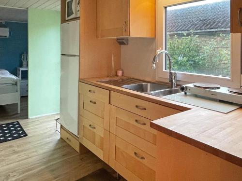 a kitchen with wooden cabinets and a sink and a window at Holiday home SÖLVESBORG X in Sölvesborg