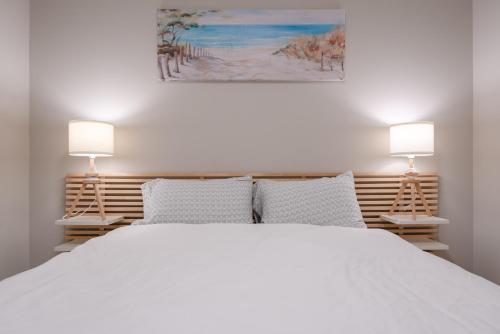 ein Schlafzimmer mit einem großen weißen Bett mit zwei Lampen in der Unterkunft Modern 3 Bedroom Home & Office & Media Room in Cochrane